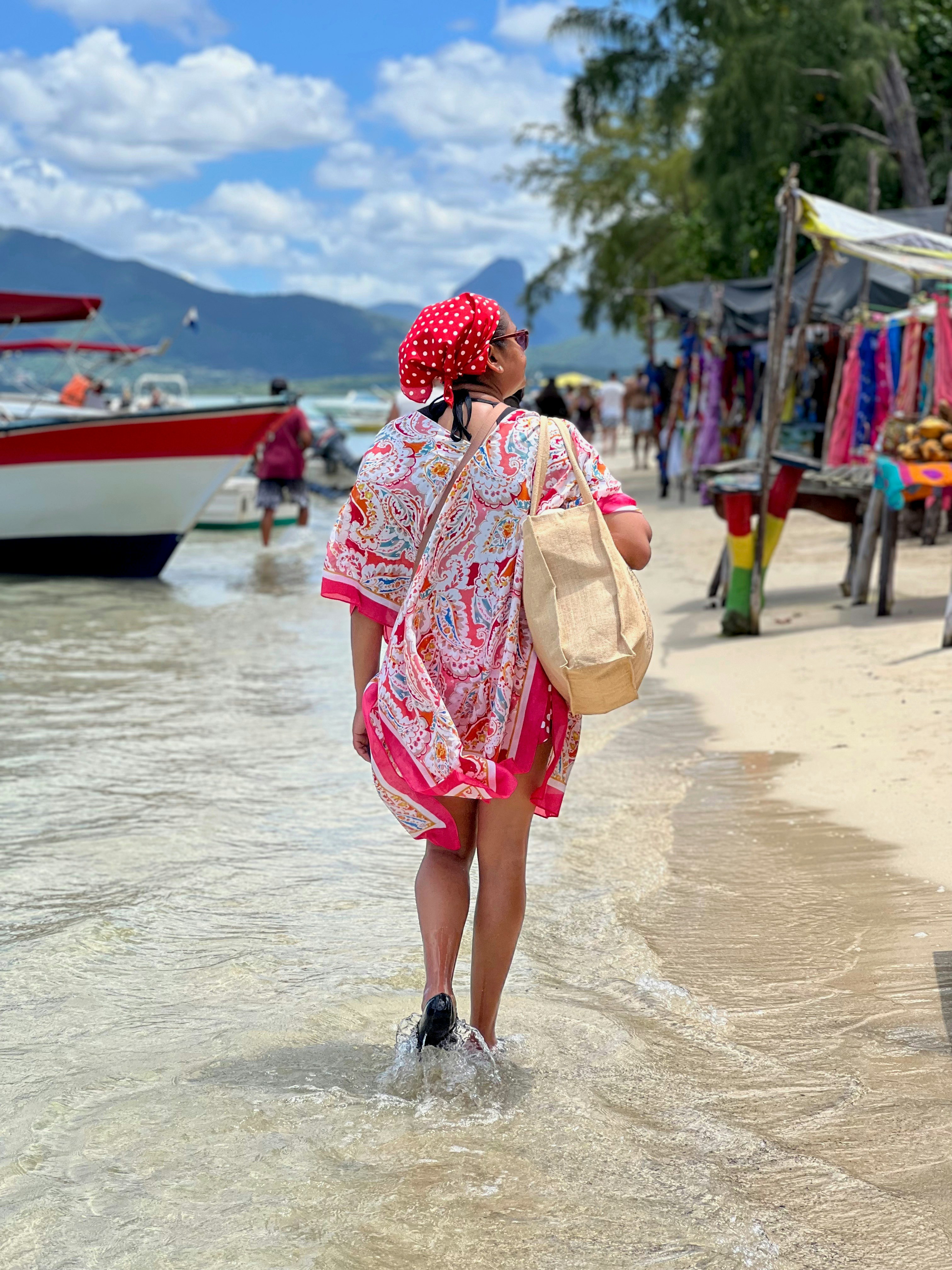 Woman walks along the beach in sunny weather.