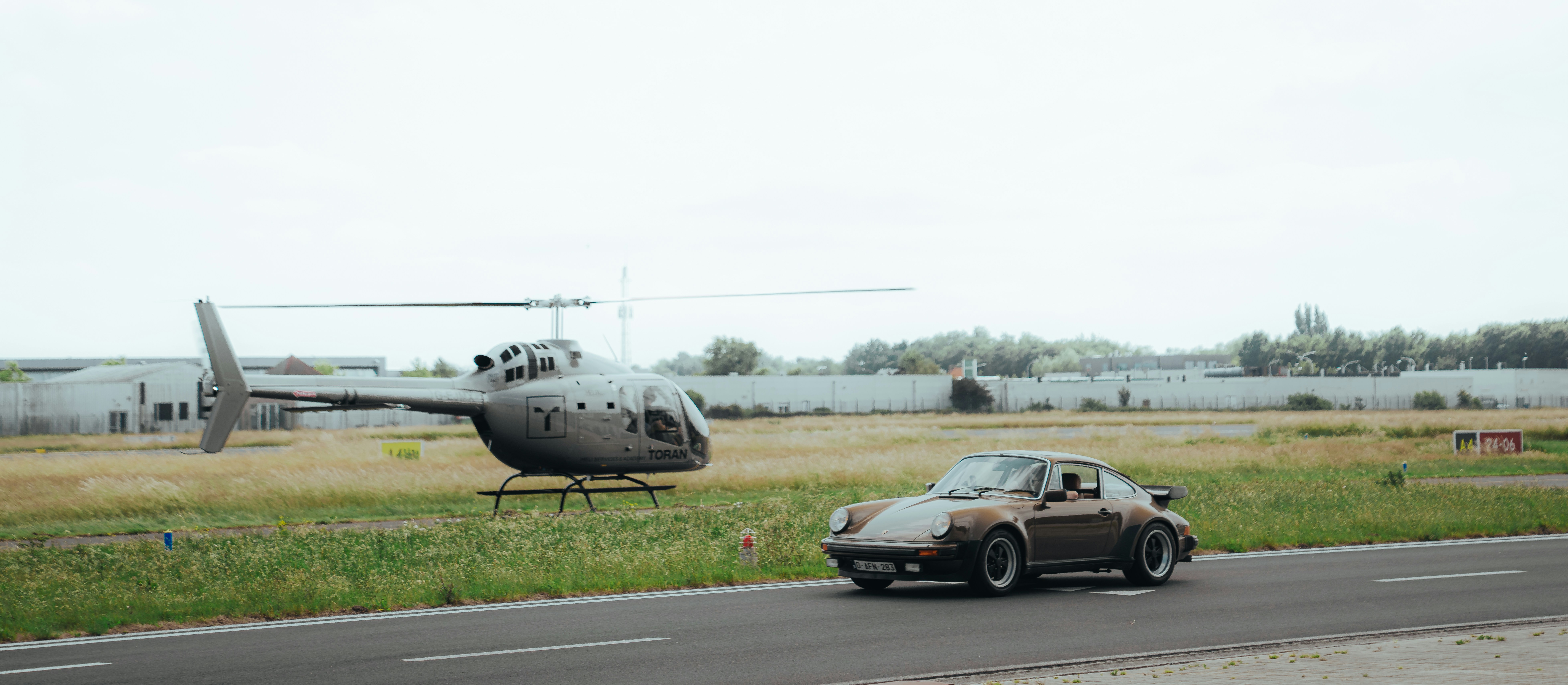 A helicopter and a car on the tarmac.