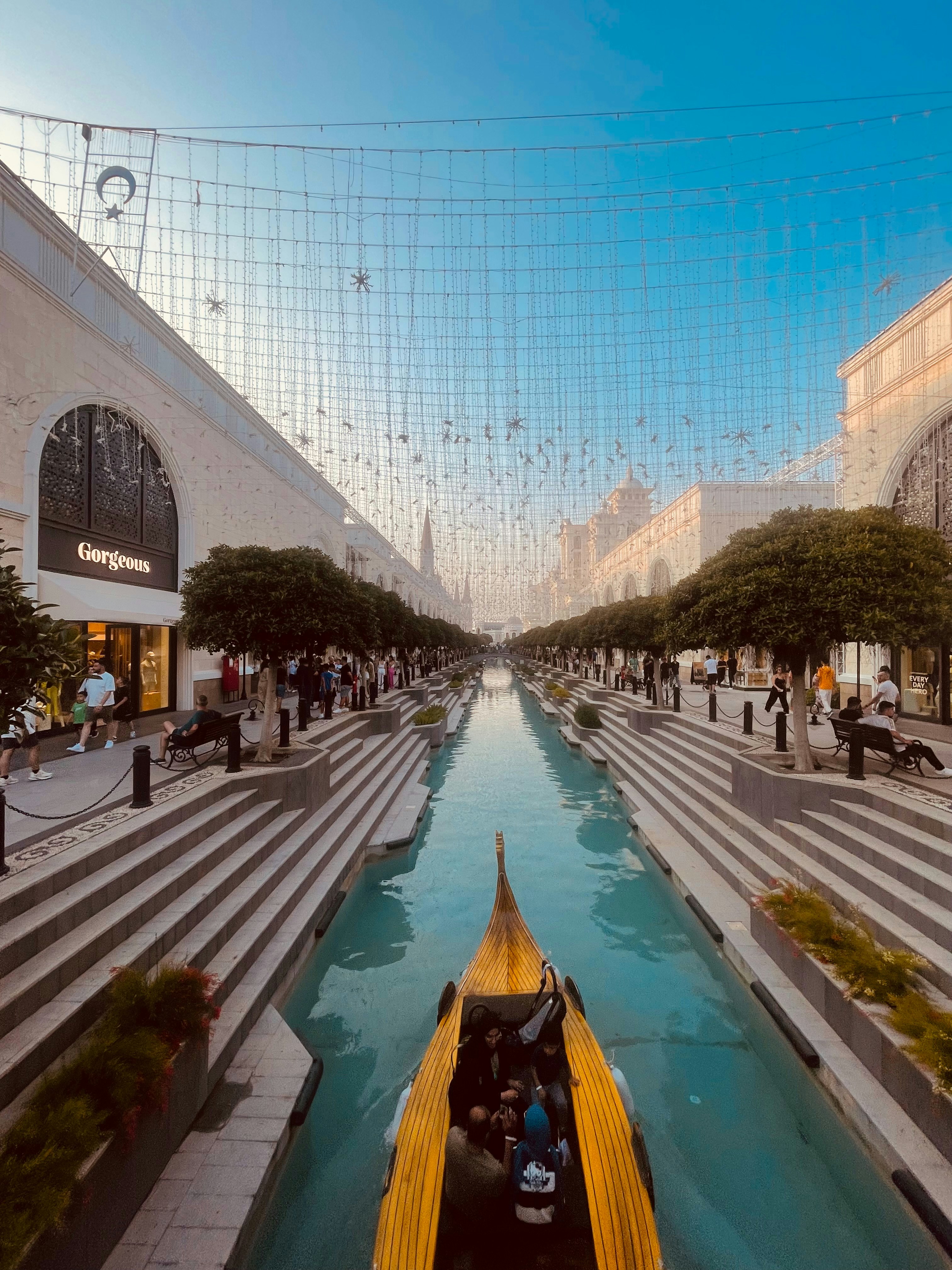 A gondola glides along a canal-lined shopping street.