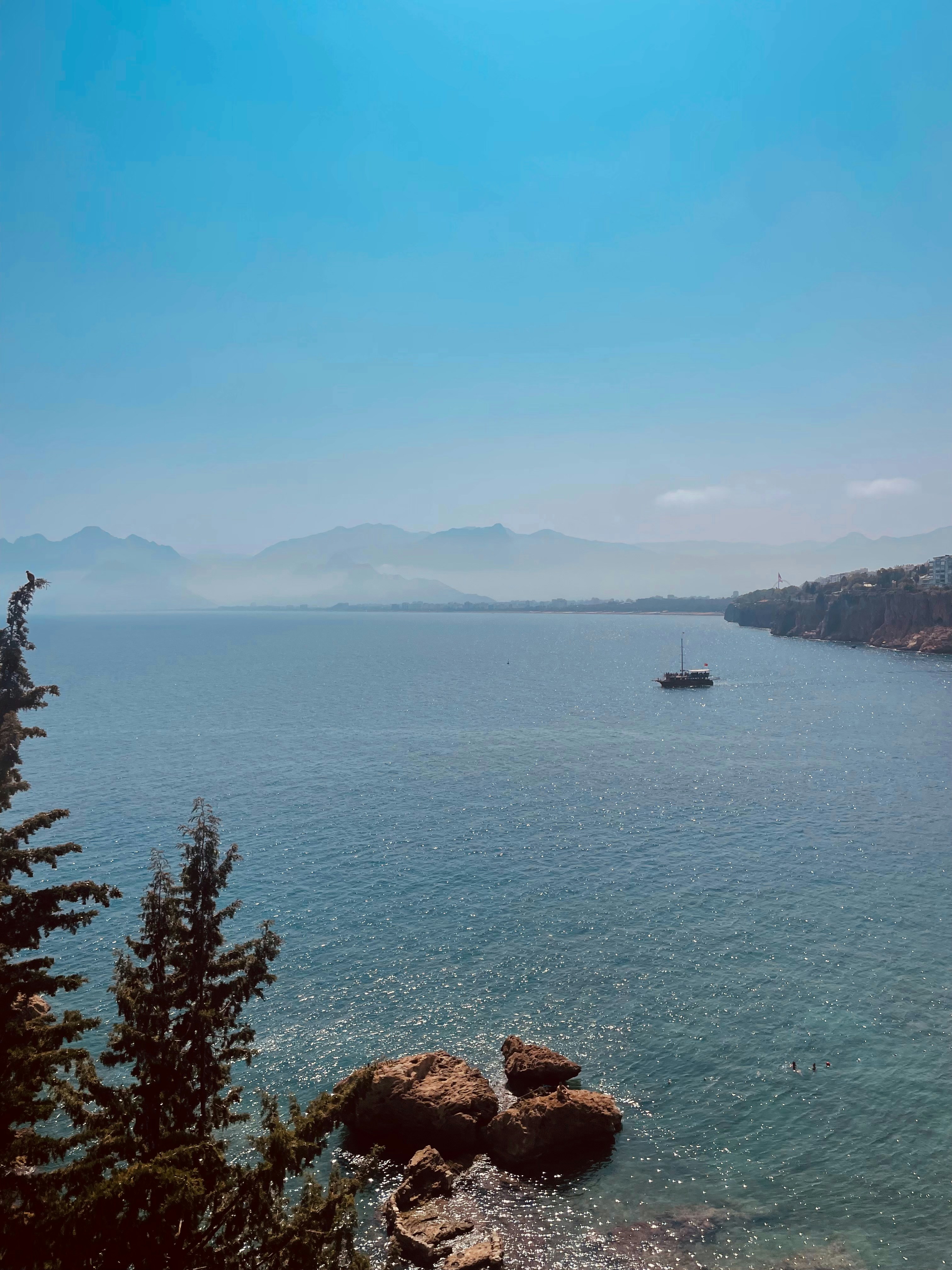 Beautiful ocean scenery with mountains and a boat.