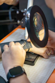 Jeweler using tools and a magnifier to fix a bracelet.