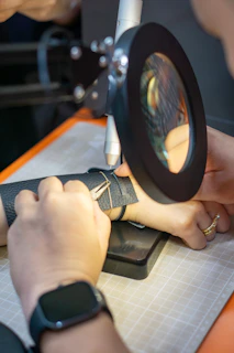 Jeweler using tools and a magnifier to fix a bracelet.