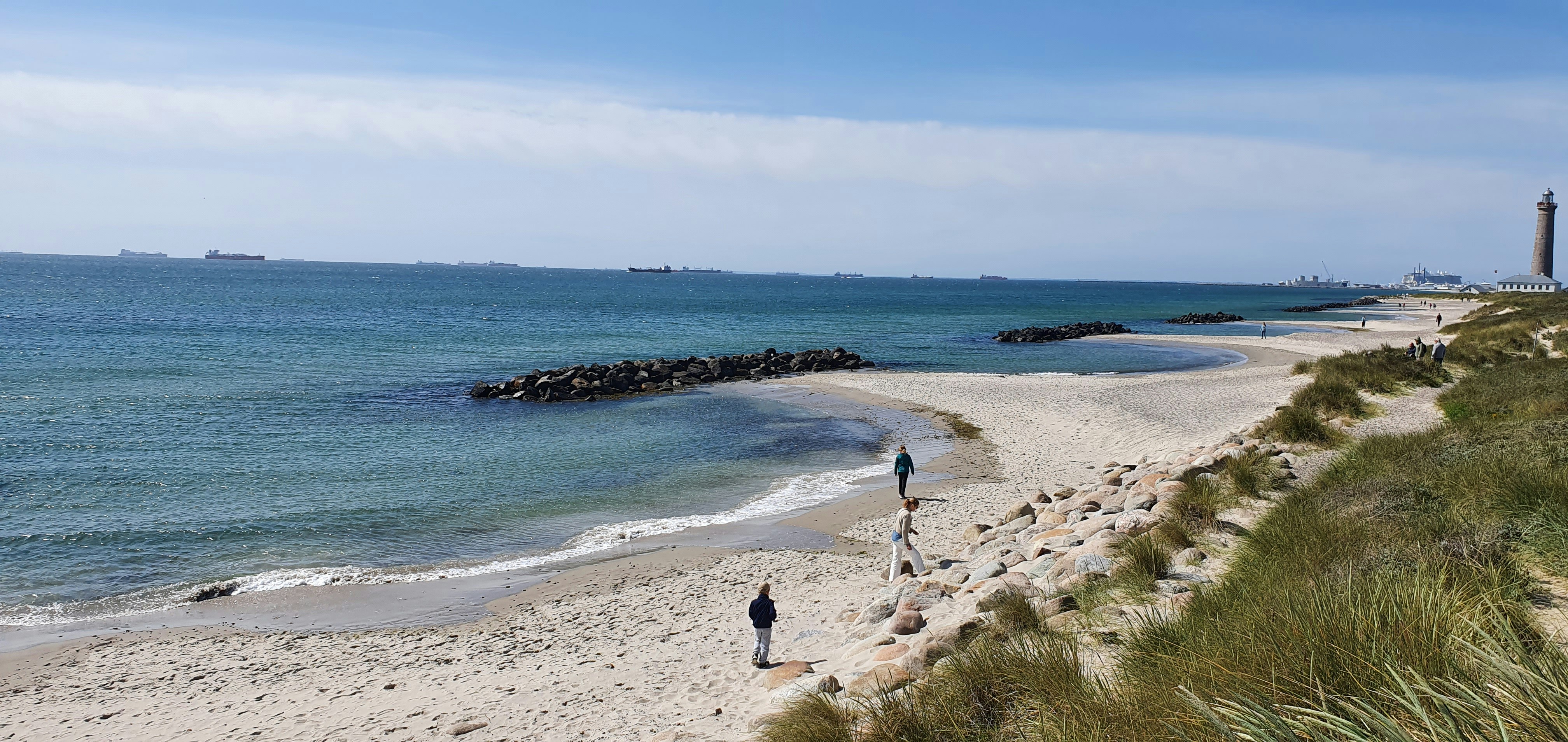 Beach, water, and sand under a sunny sky.