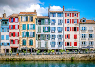 Colorful buildings line a river under a sunny sky.