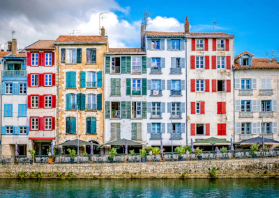 Colorful buildings line a river under a sunny sky.
