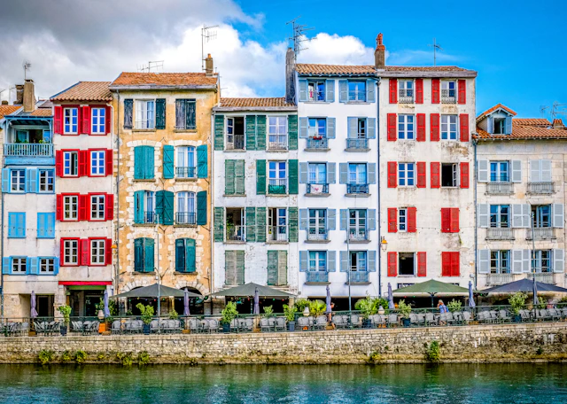 Colorful buildings line a river under a sunny sky.