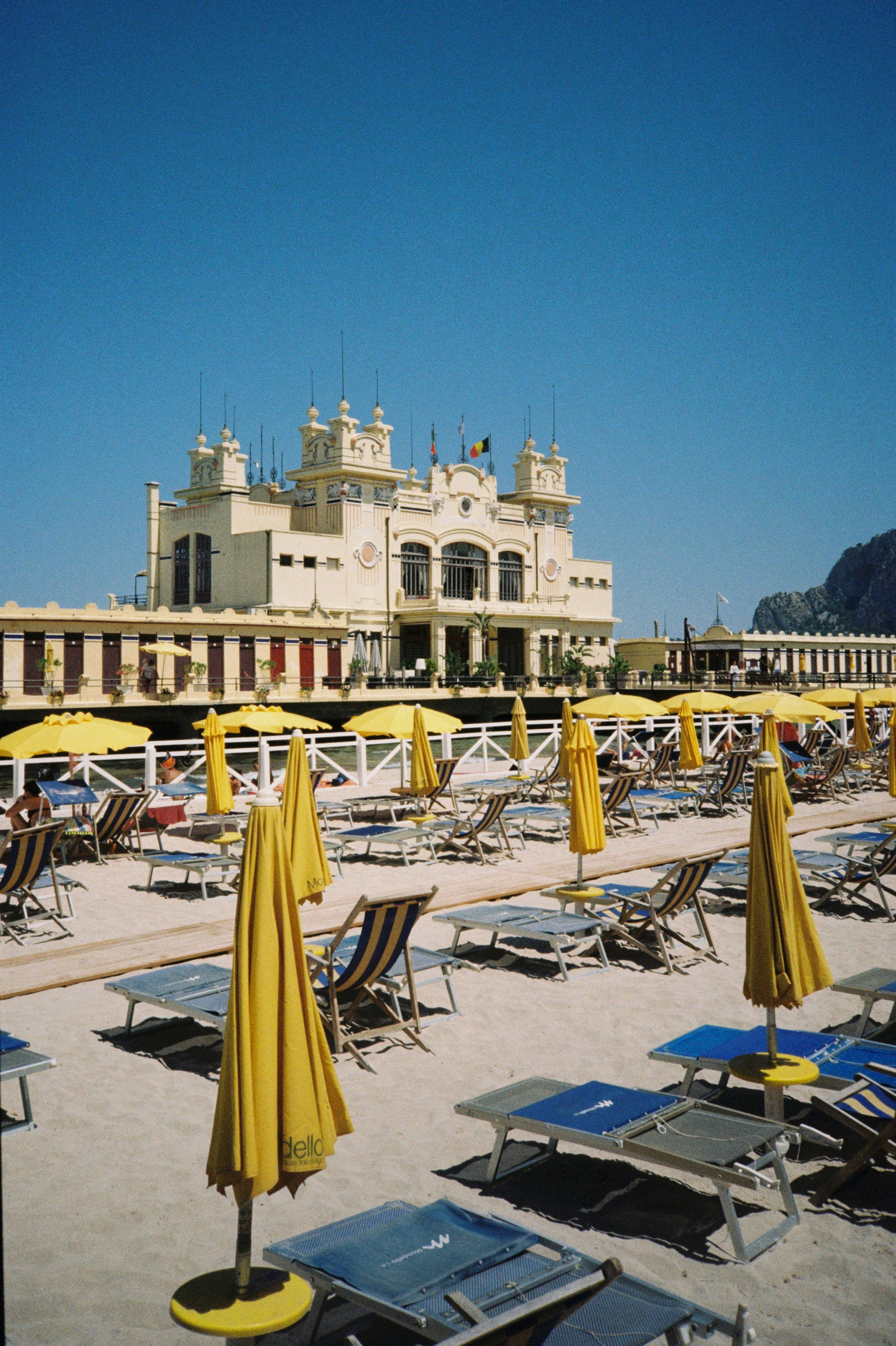 Beach with yellow umbrellas and a building.