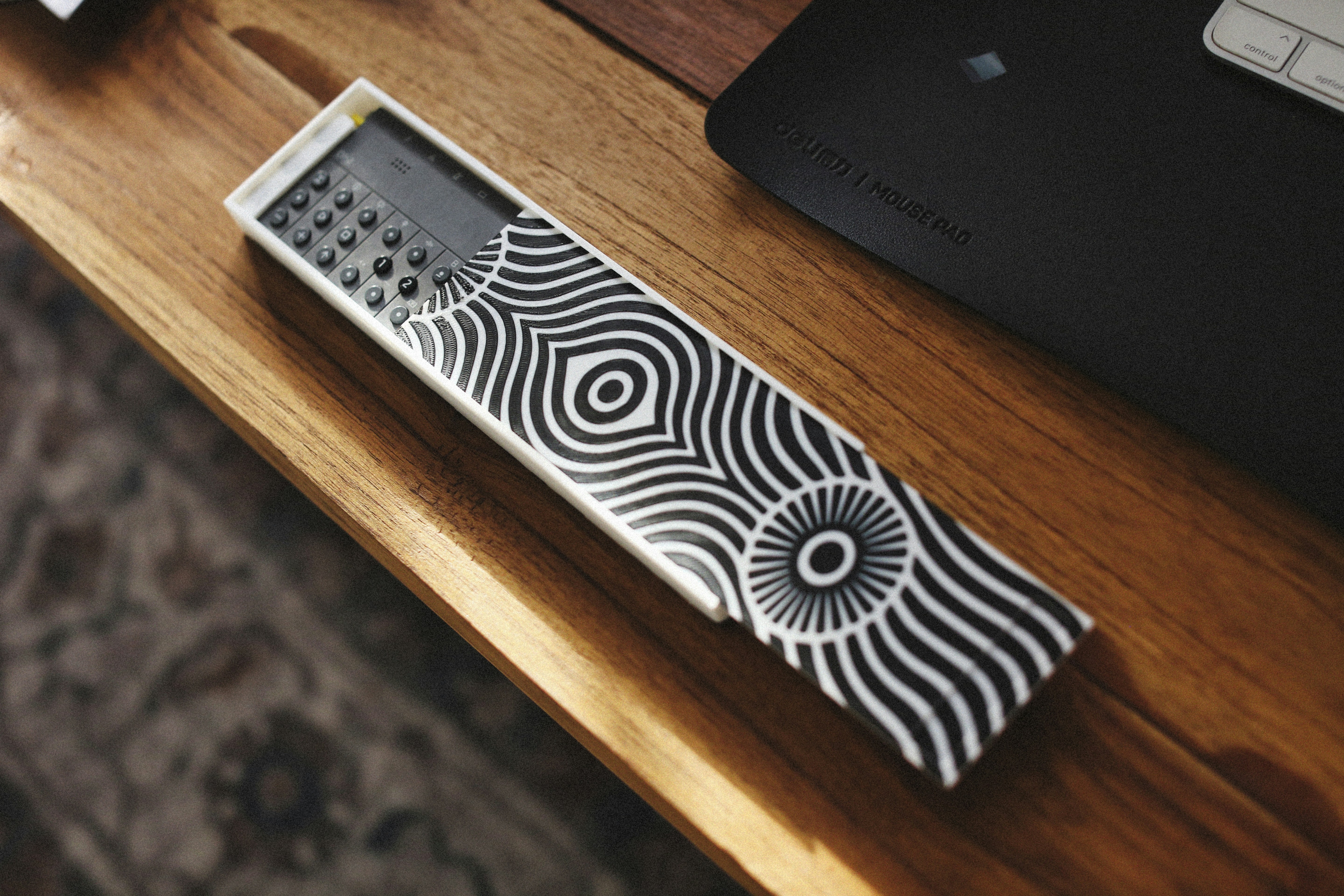 A remote control lies on a wooden surface.