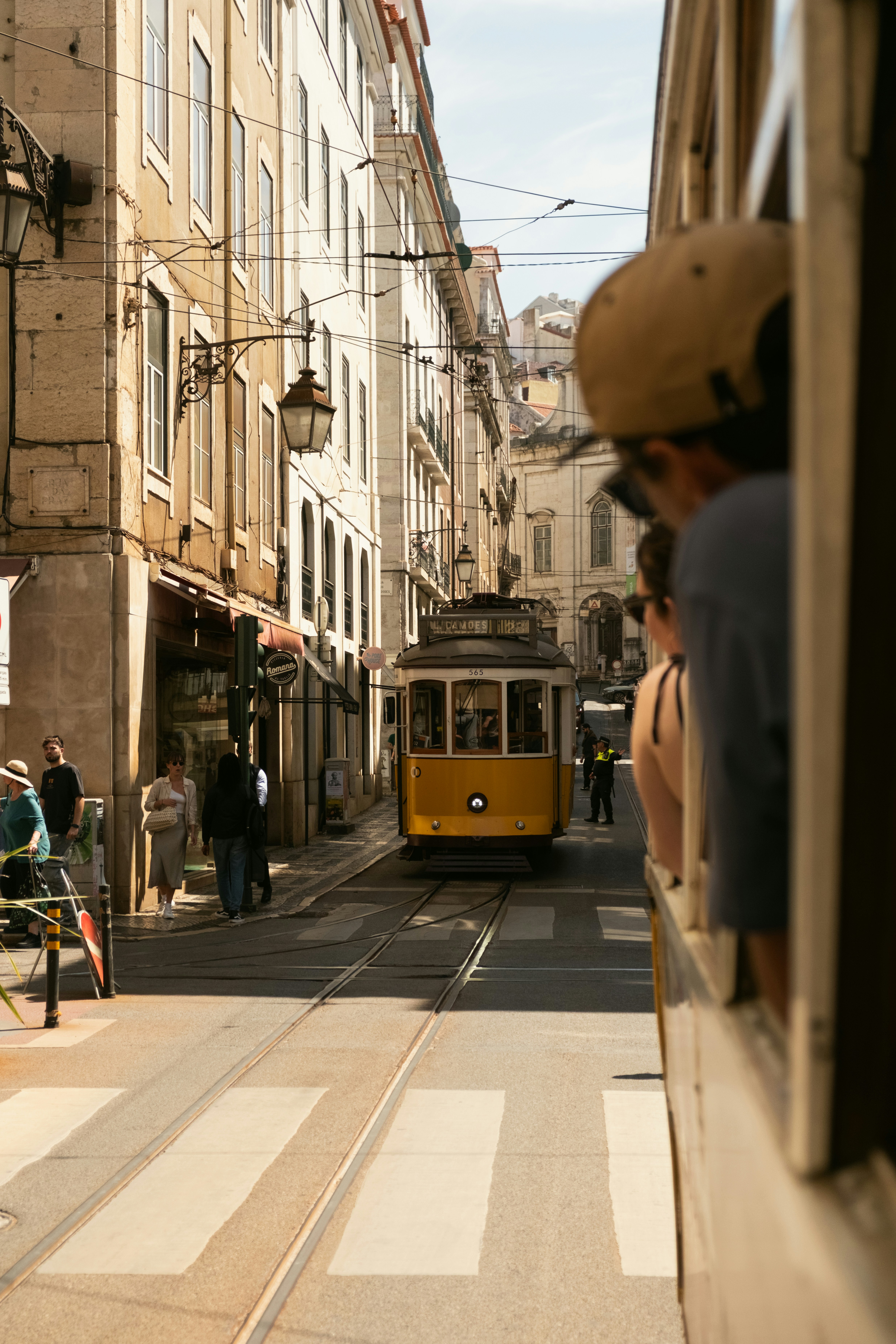 Yellow tram travels down a narrow city street.