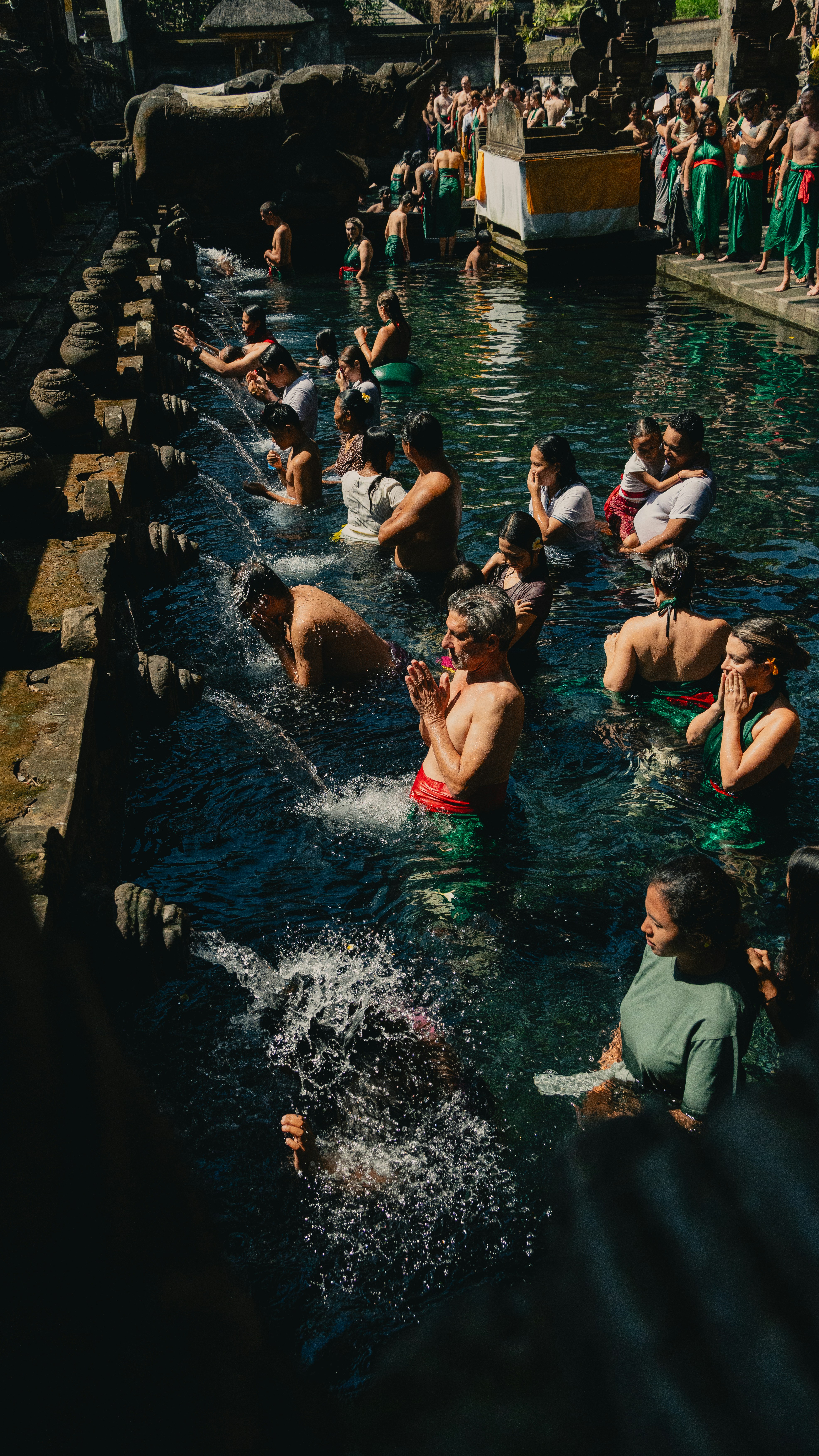 People are bathing and praying in a holy water pool.