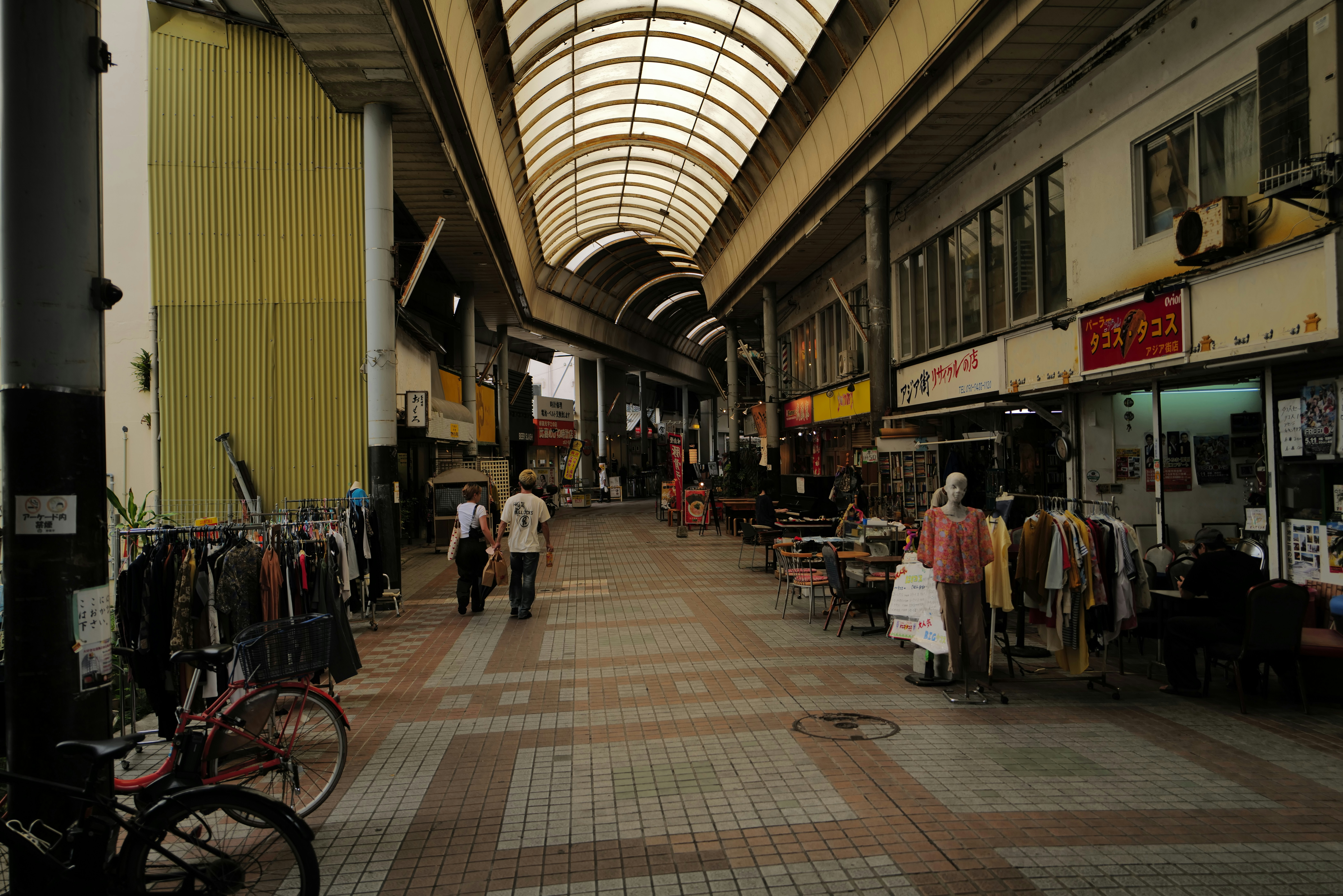 A covered walkway with shops and pedestrians.