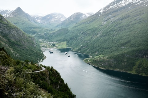 A lush fjord winds between majestic, snow-capped mountains.