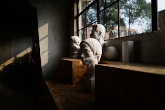 Sculptures sit in a sunlit workshop window.