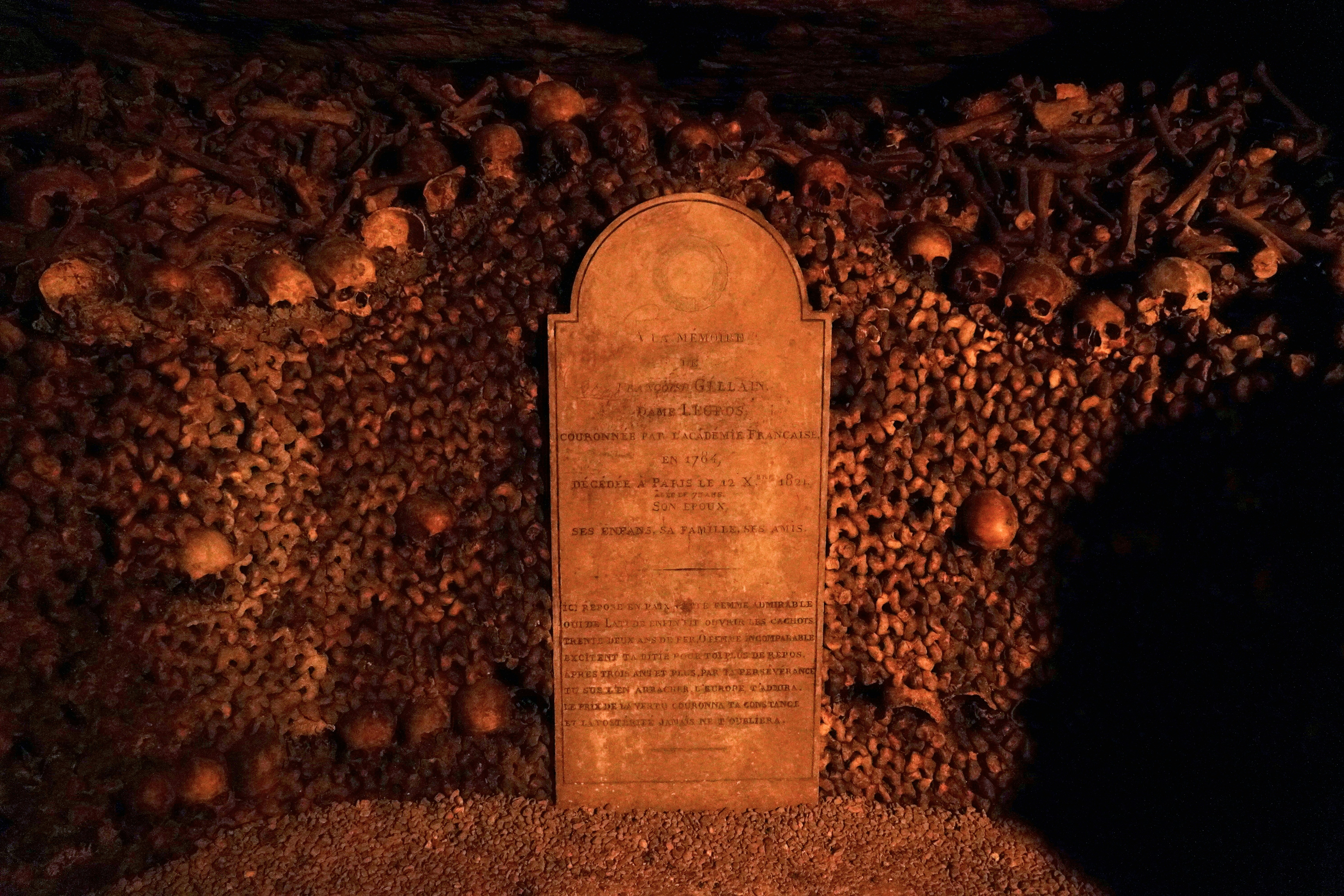A tombstone stands amidst skulls and bones.