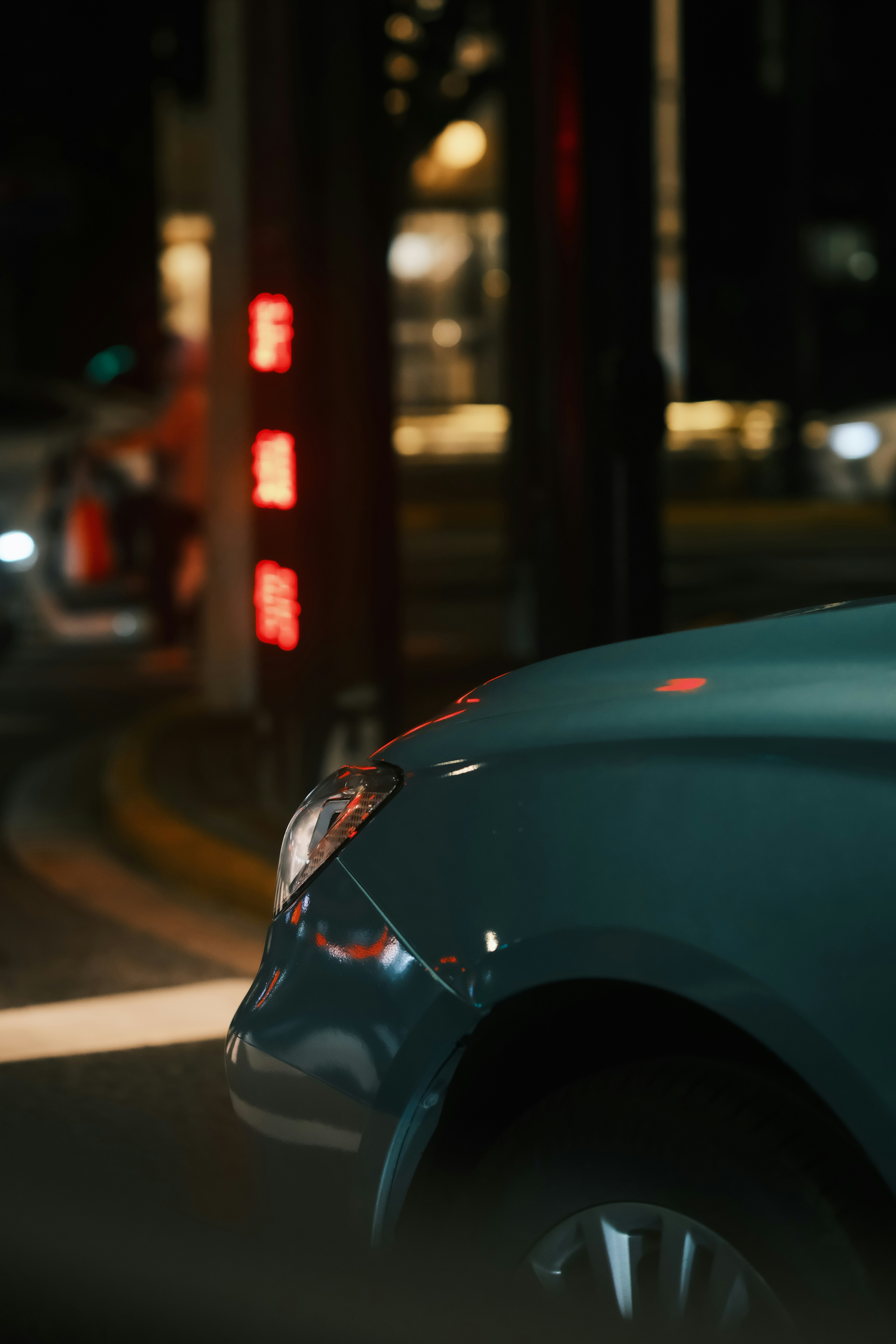 Car waits at night in a dimly lit city.