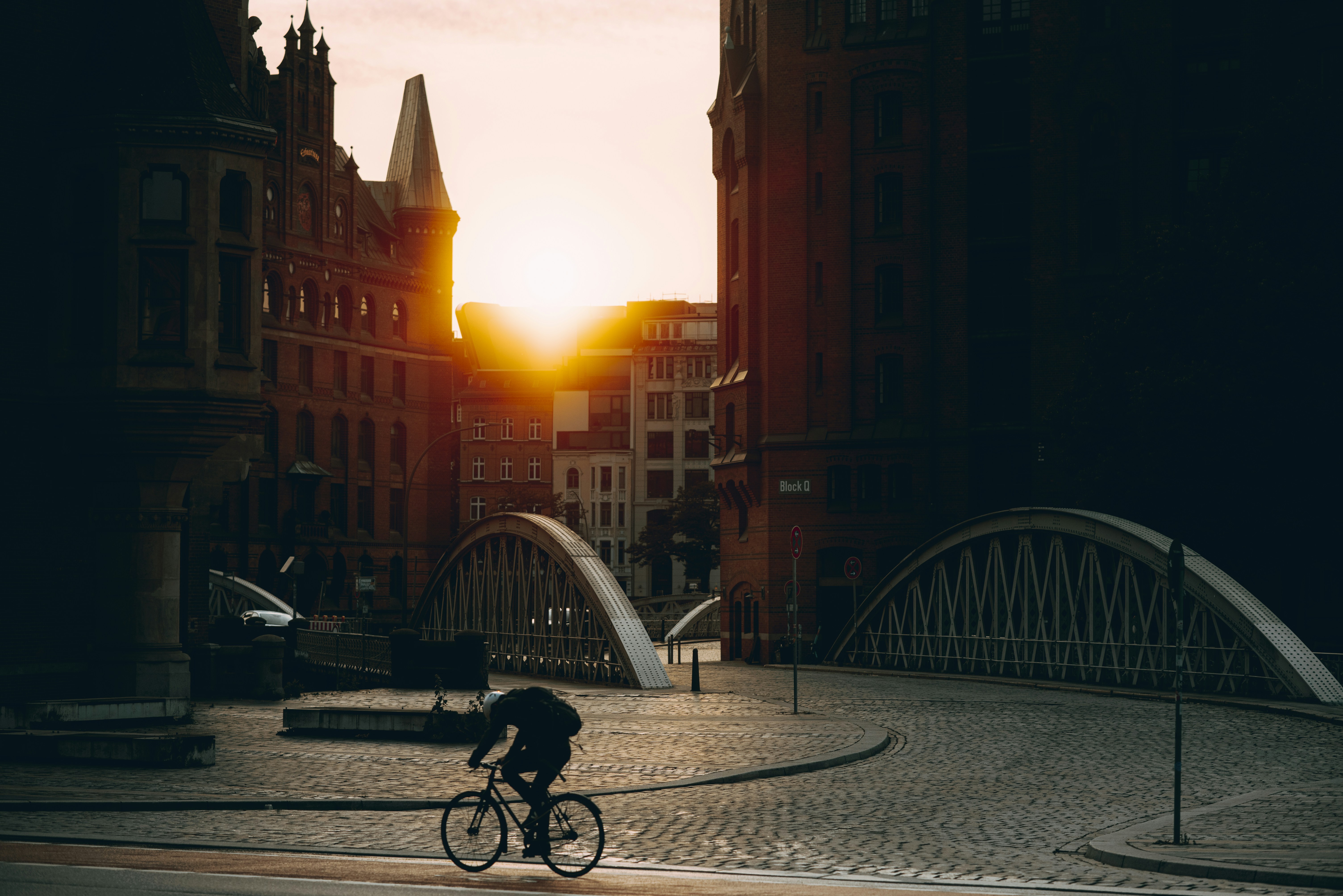 A cyclist rides in the city during sunset.