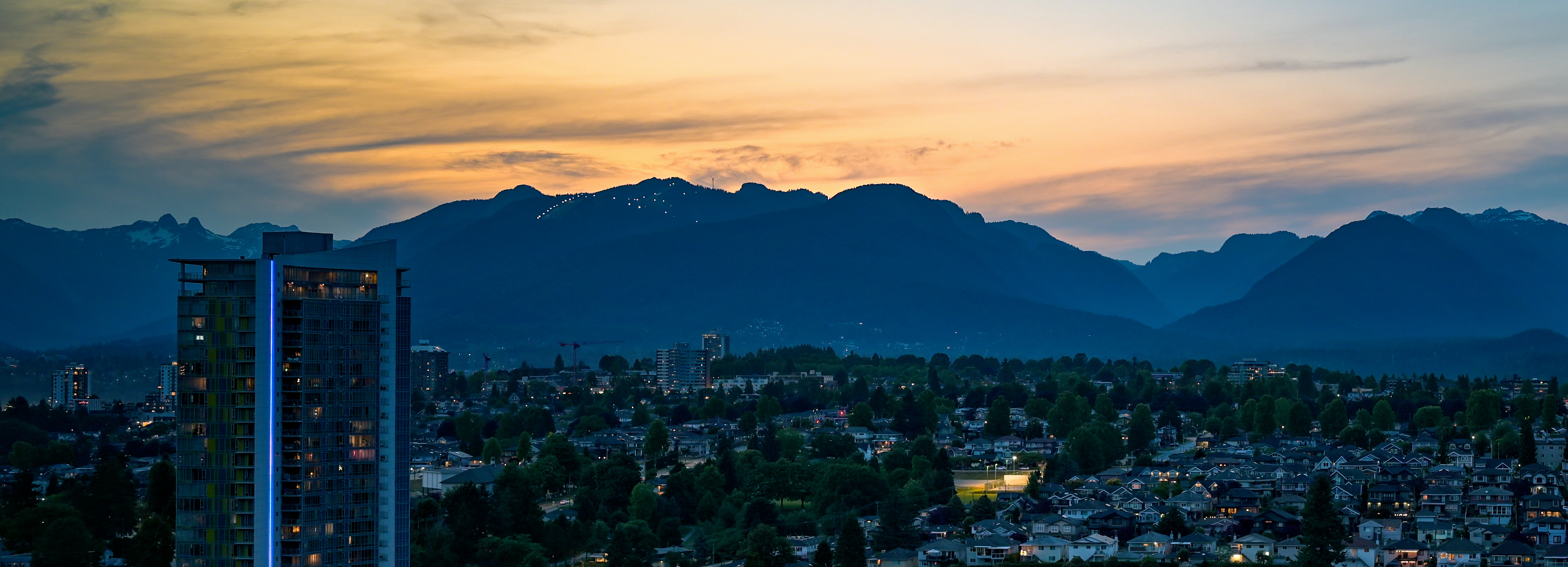 City skyline with mountains at dusk.