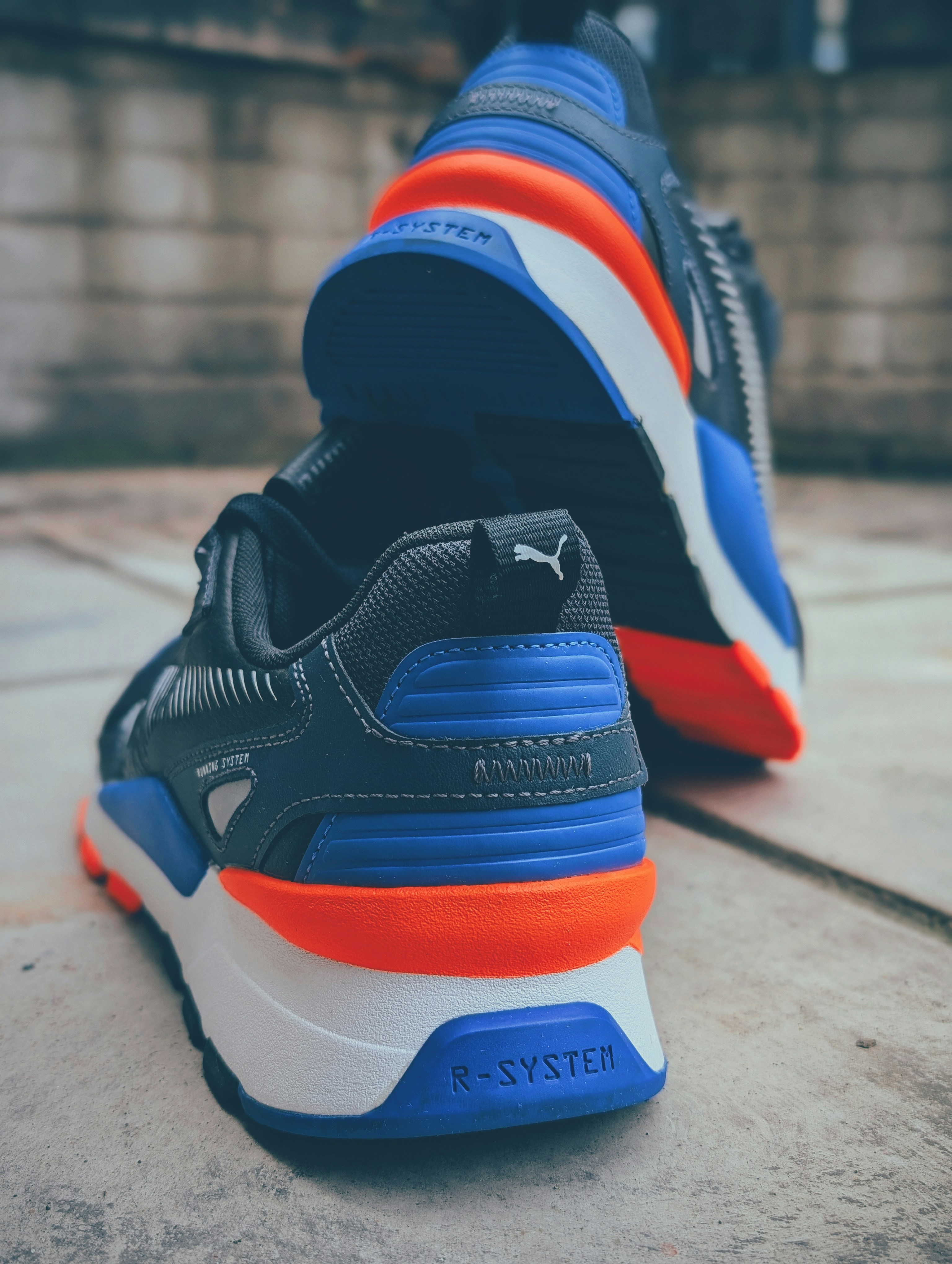 Tênis Puma com detalhes em azul, laranja e branco.