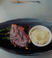 Ribs, asparagus, and mashed potatoes are plated.