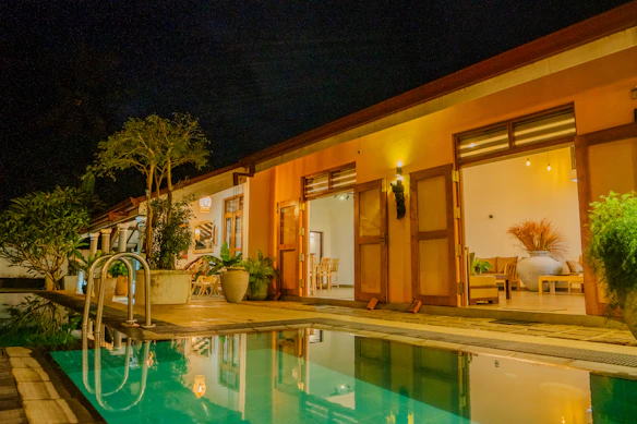 A lit-up pool and house at night.