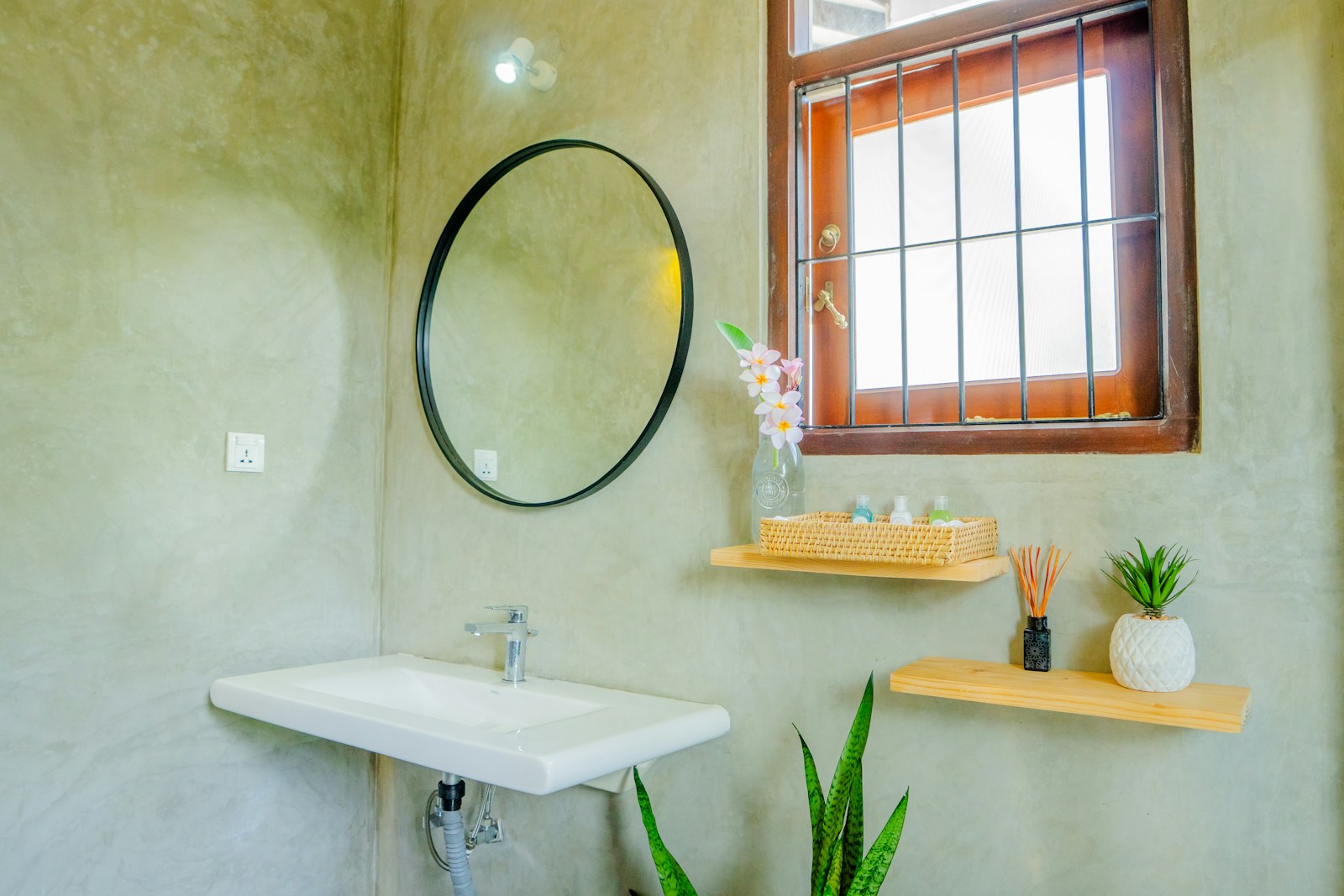 small bathroom with floating wood shelves plants and round mirror