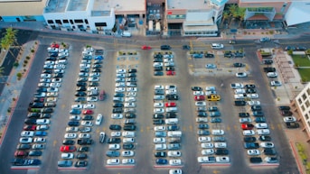 Cars are parked in a large, crowded parking lot.