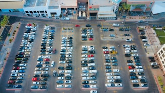 Cars are parked in a large, crowded parking lot.