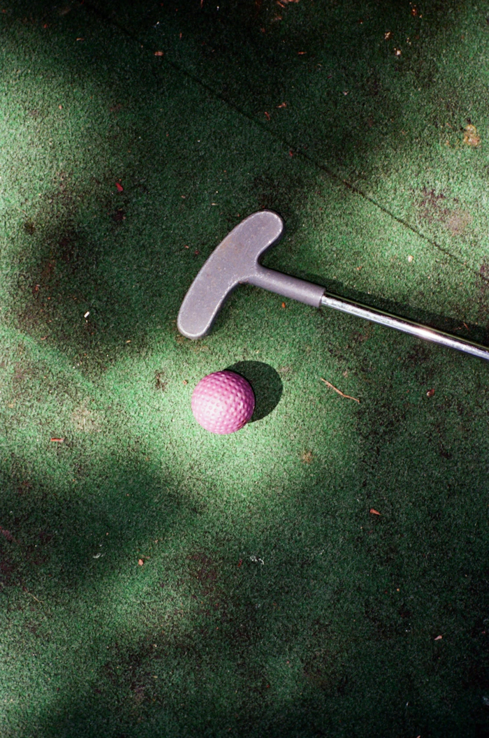 Mini golf club and ball on a putting green