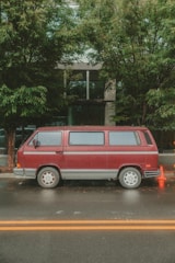 A red van is parked on a wet street.