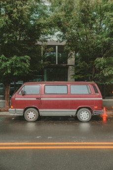A red van is parked on a wet street.