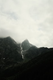 Misty mountains loom under a cloudy sky.