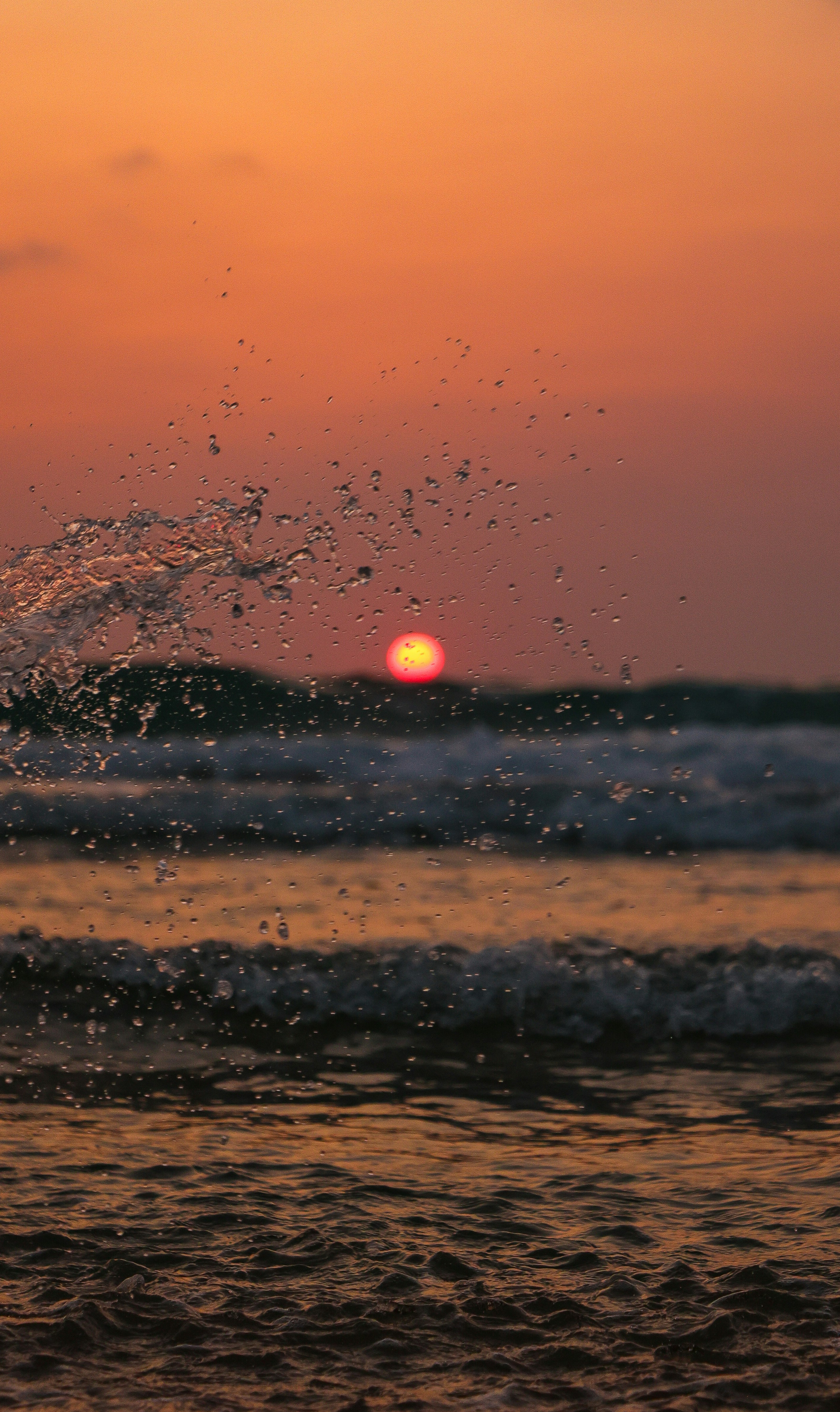 Waves crash against a beautiful sunset.