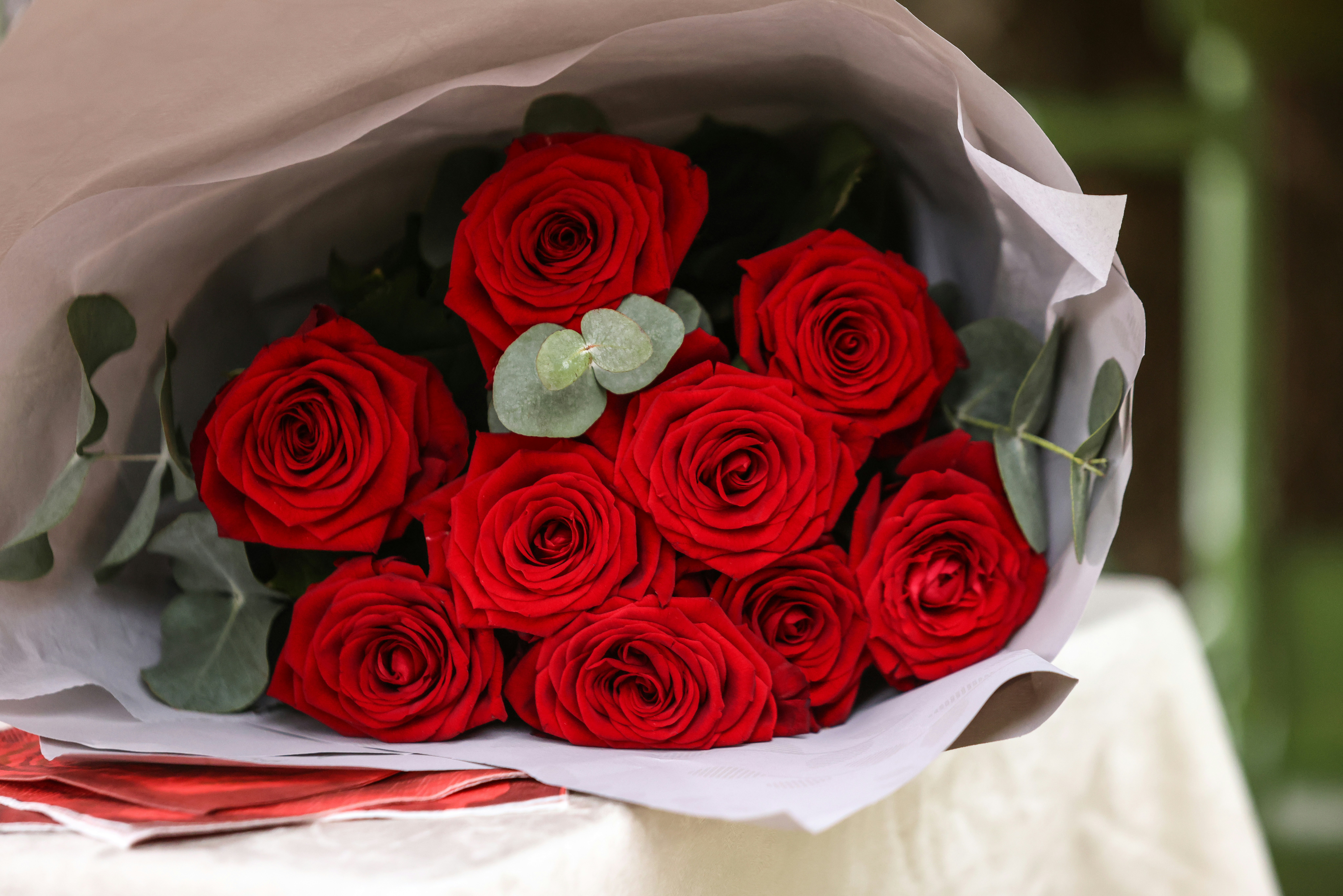 A bouquet of red roses wrapped in white.