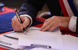 A person signs a document with a pen.