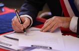 A person signs a document with a pen.