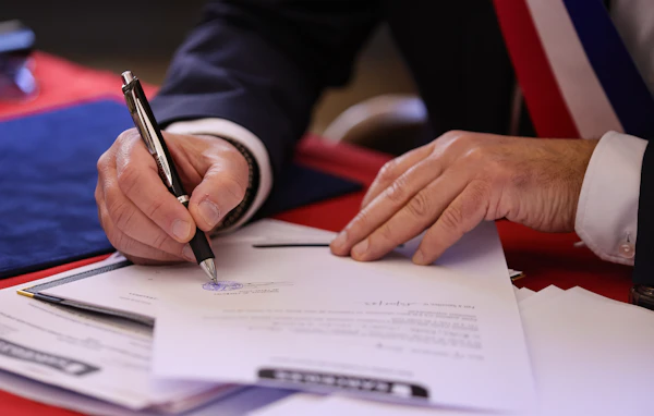 A person signing a document with a pen
