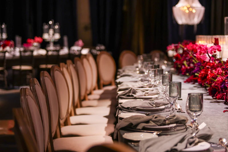 Long dinner table with velvet chairs and a red floral runner