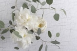 White peonies with greenery on a textured background.