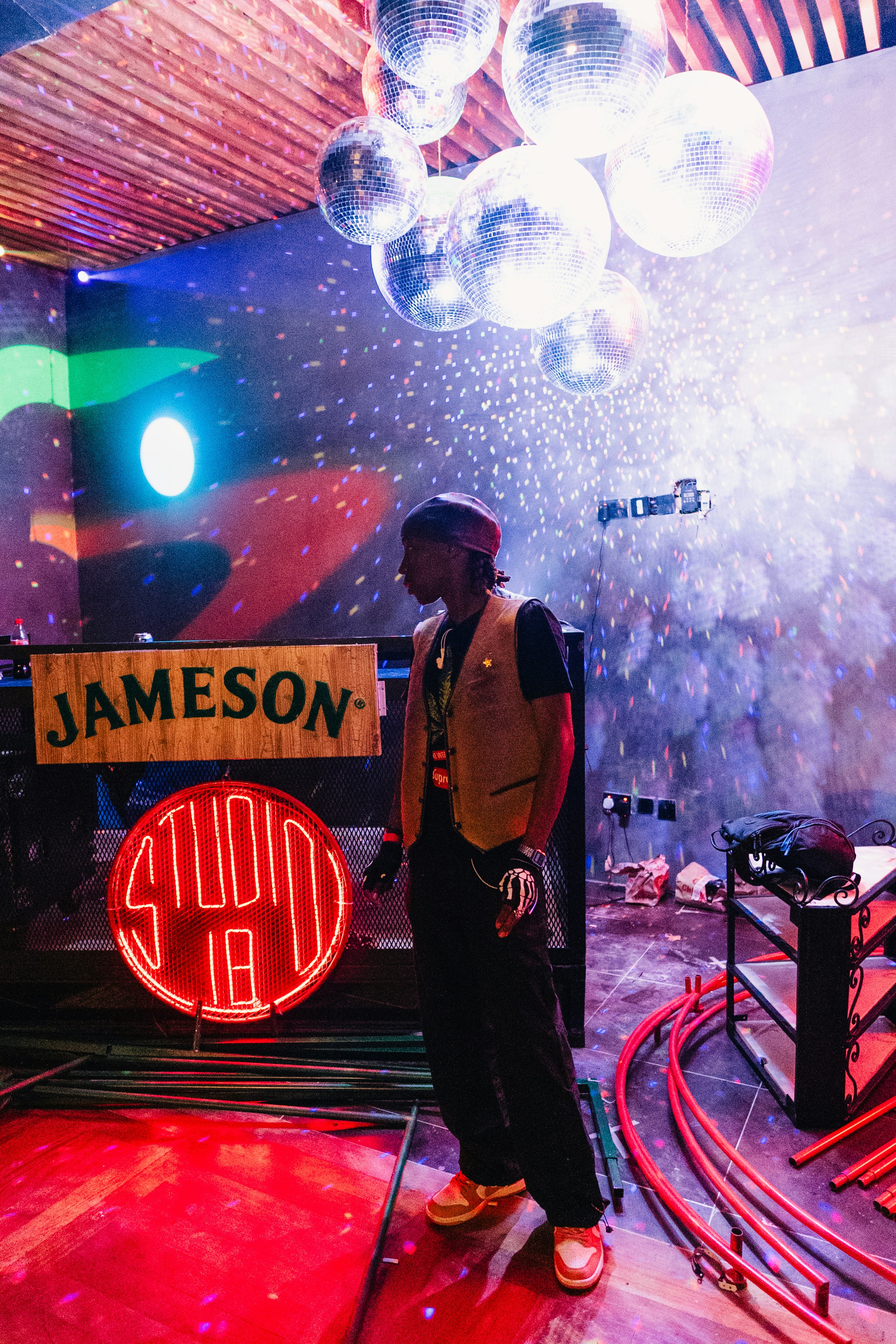 Dj stands in a club with lights and disco balls.