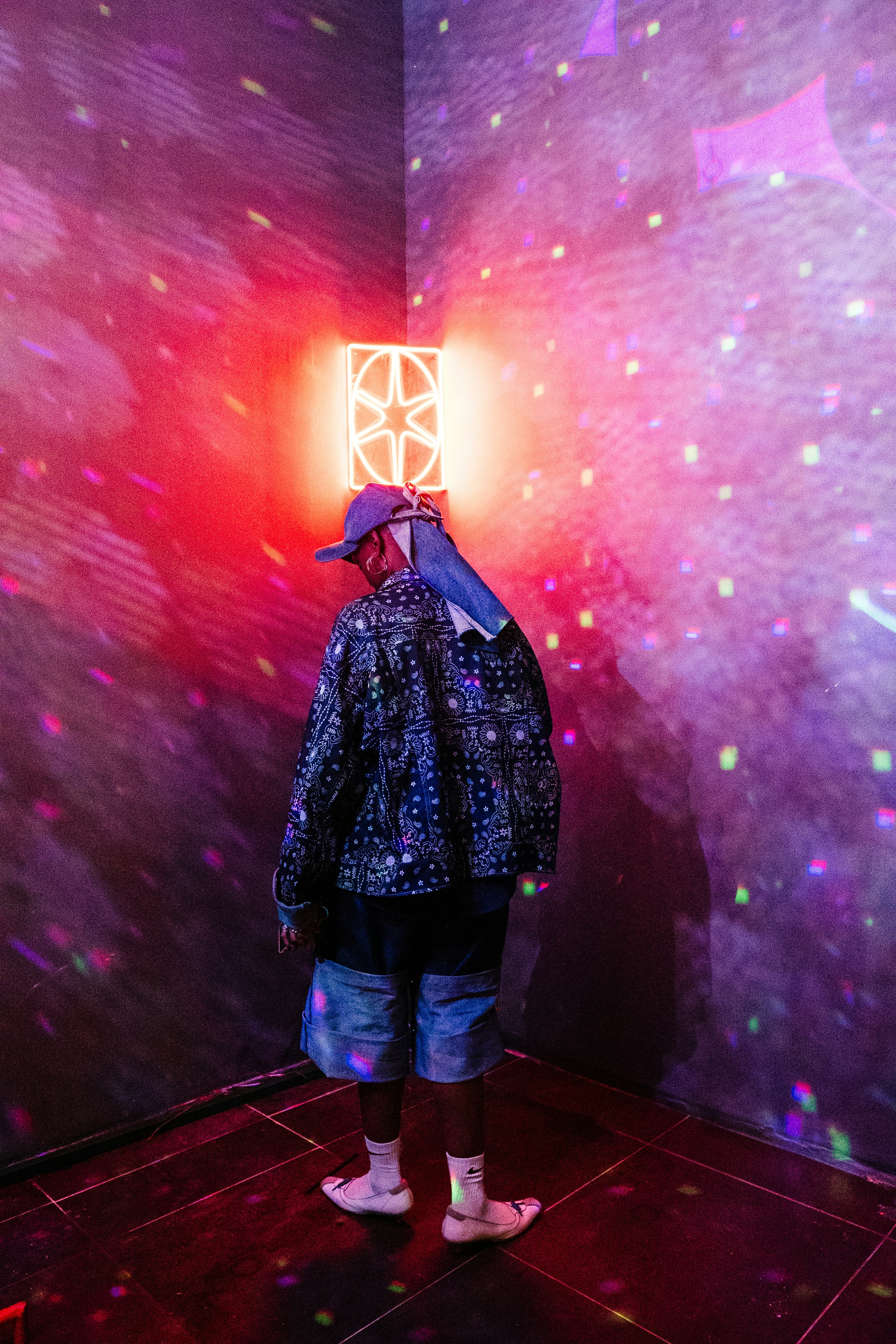 Person stands in a room with colorful, neon lights.