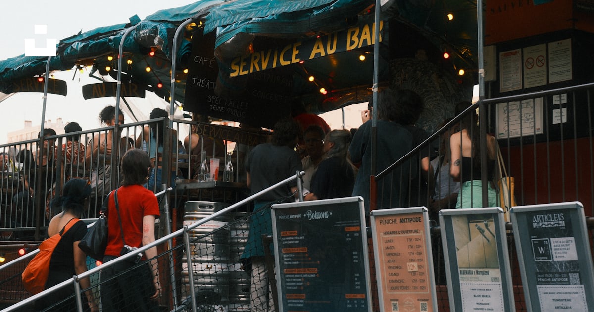 People queue at an outdoor bar with food menus. photo – Free People ...