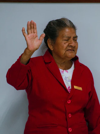 Elderly woman in red jacket raising her hand
