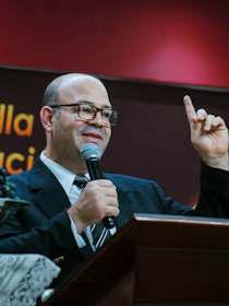 Man in suit speaking into a microphone at a podium.