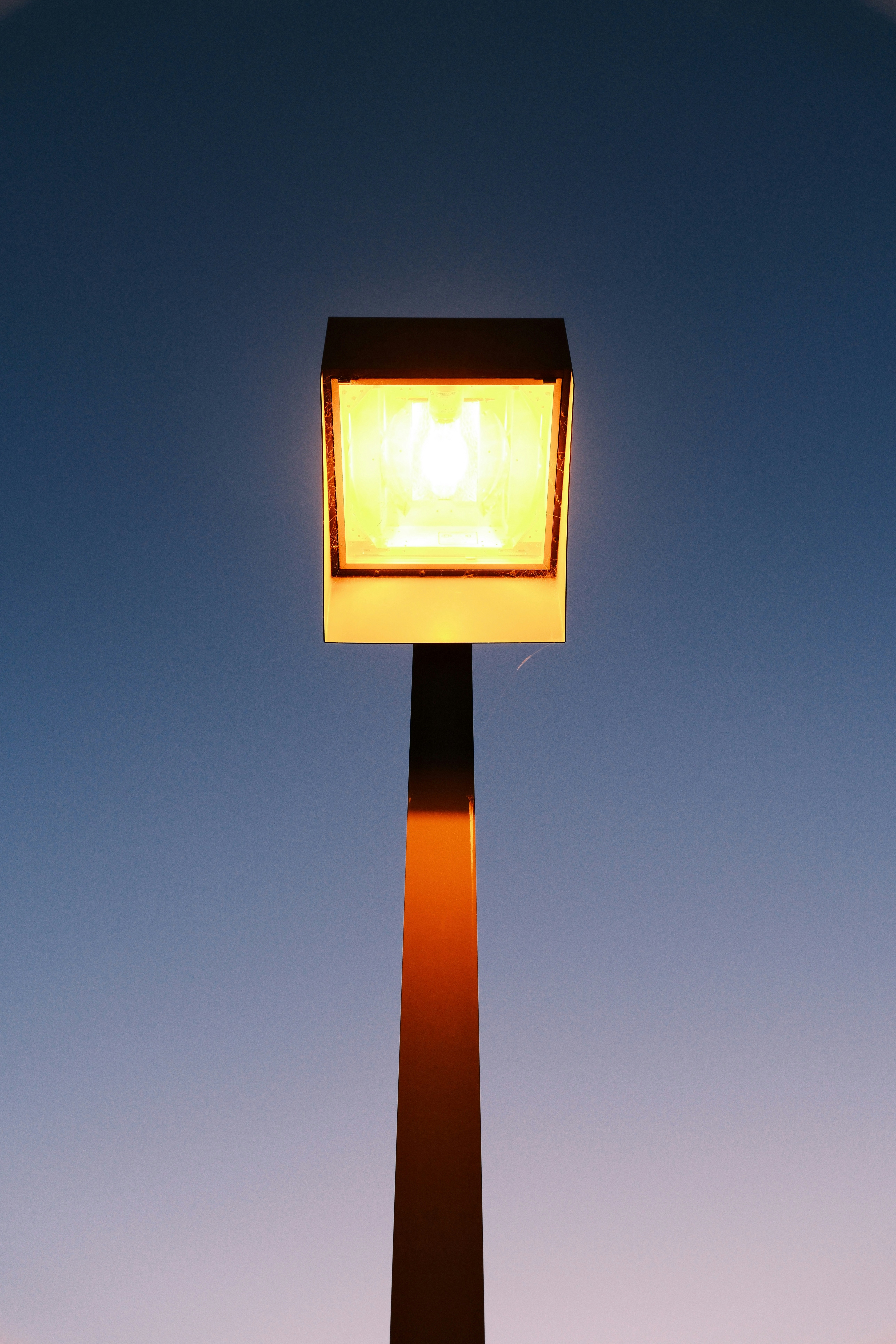 A glowing street lamp against a blue sky.