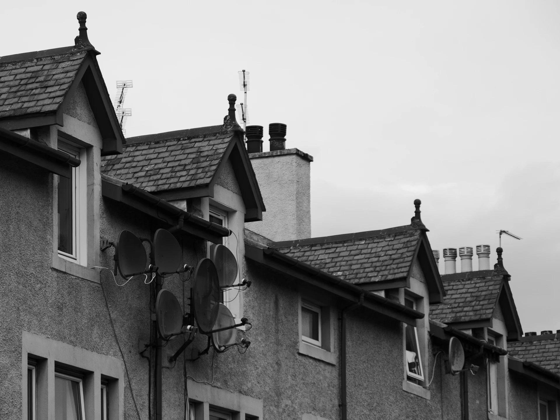 Row of UK houses with gabled rooflines and chimneys