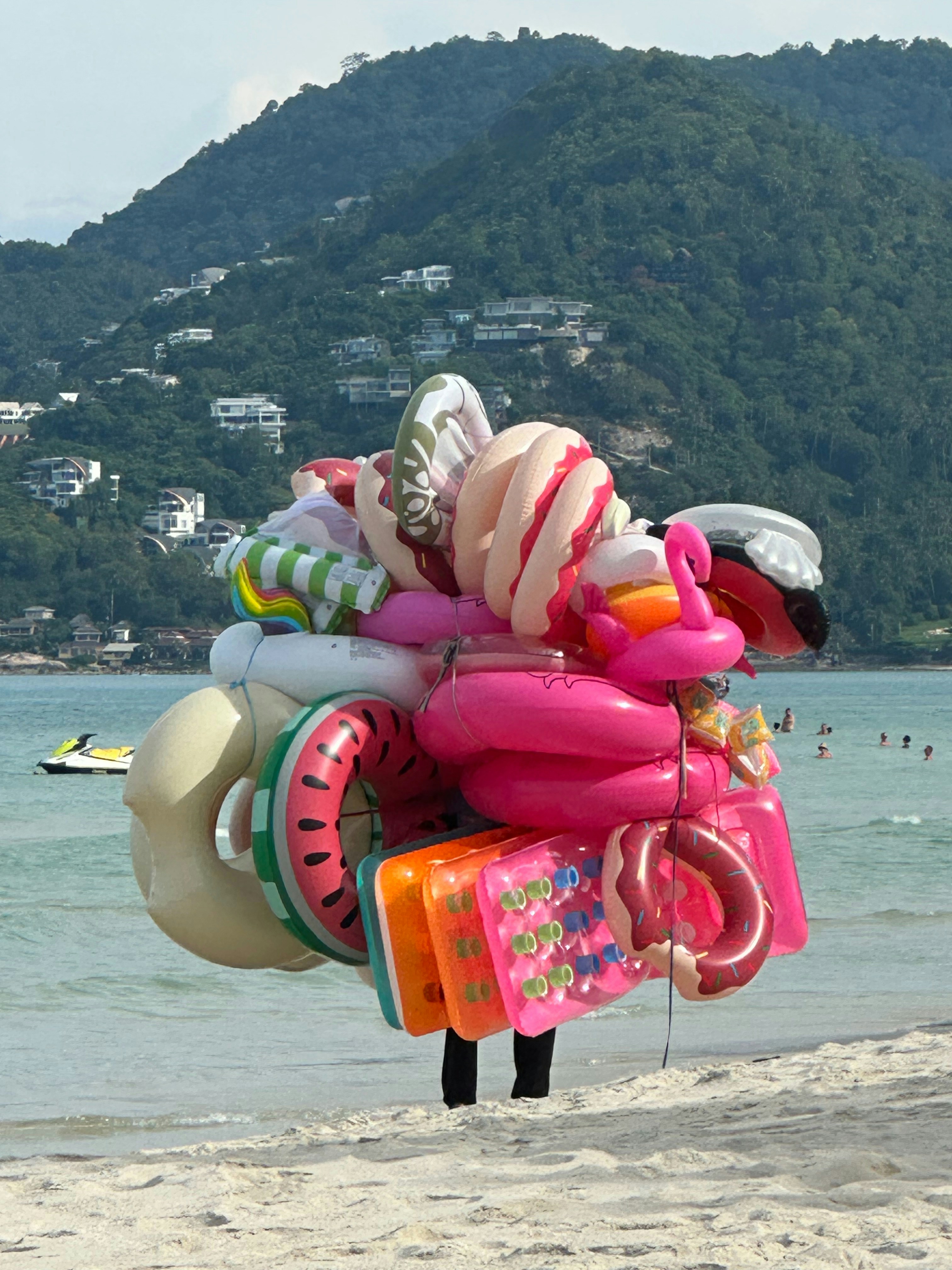 Someone carries a huge bundle of beach floats.