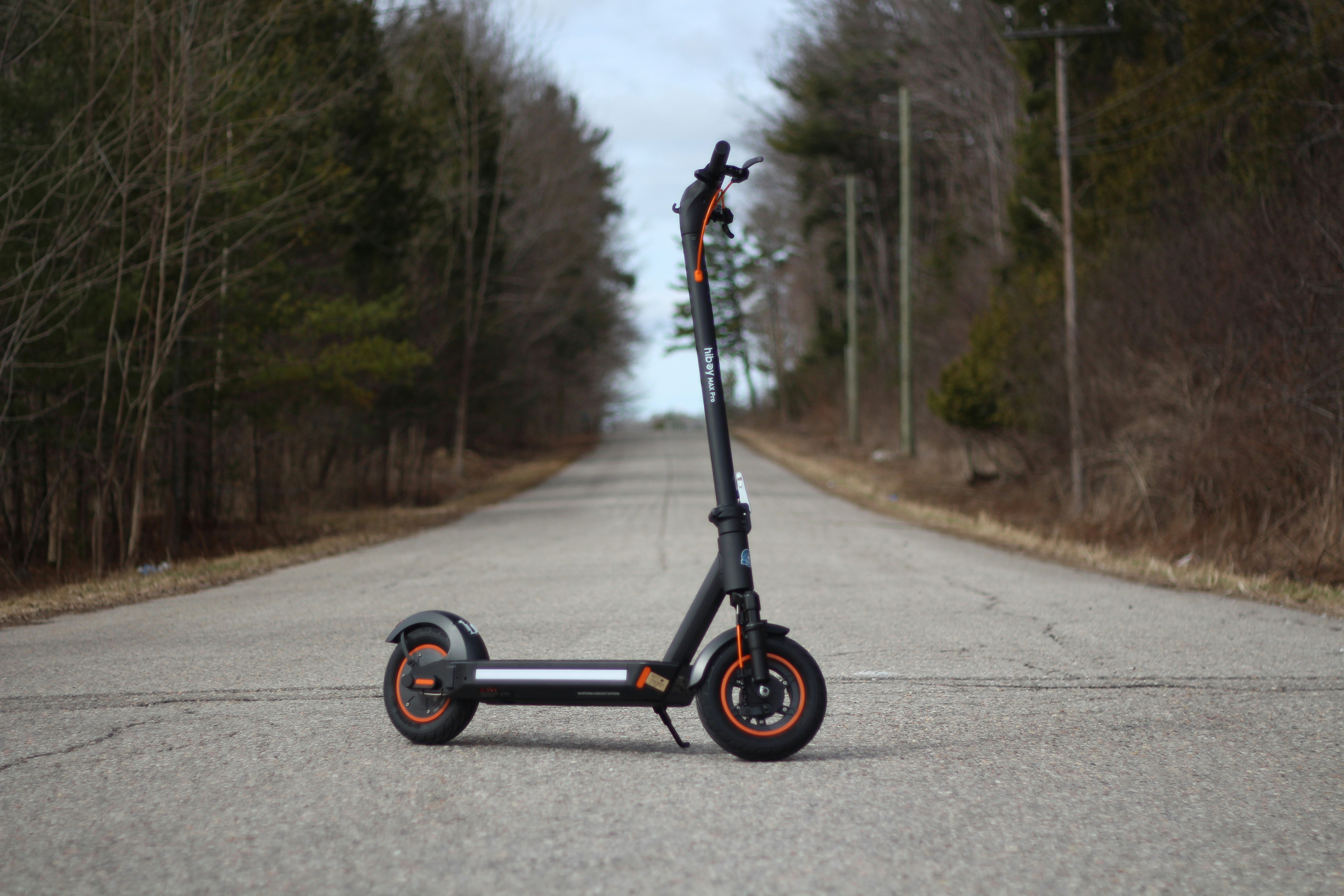A black scooter sits centered on an empty road.