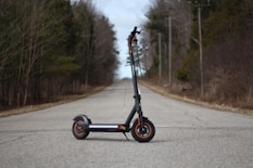A black scooter sits centered on an empty road.