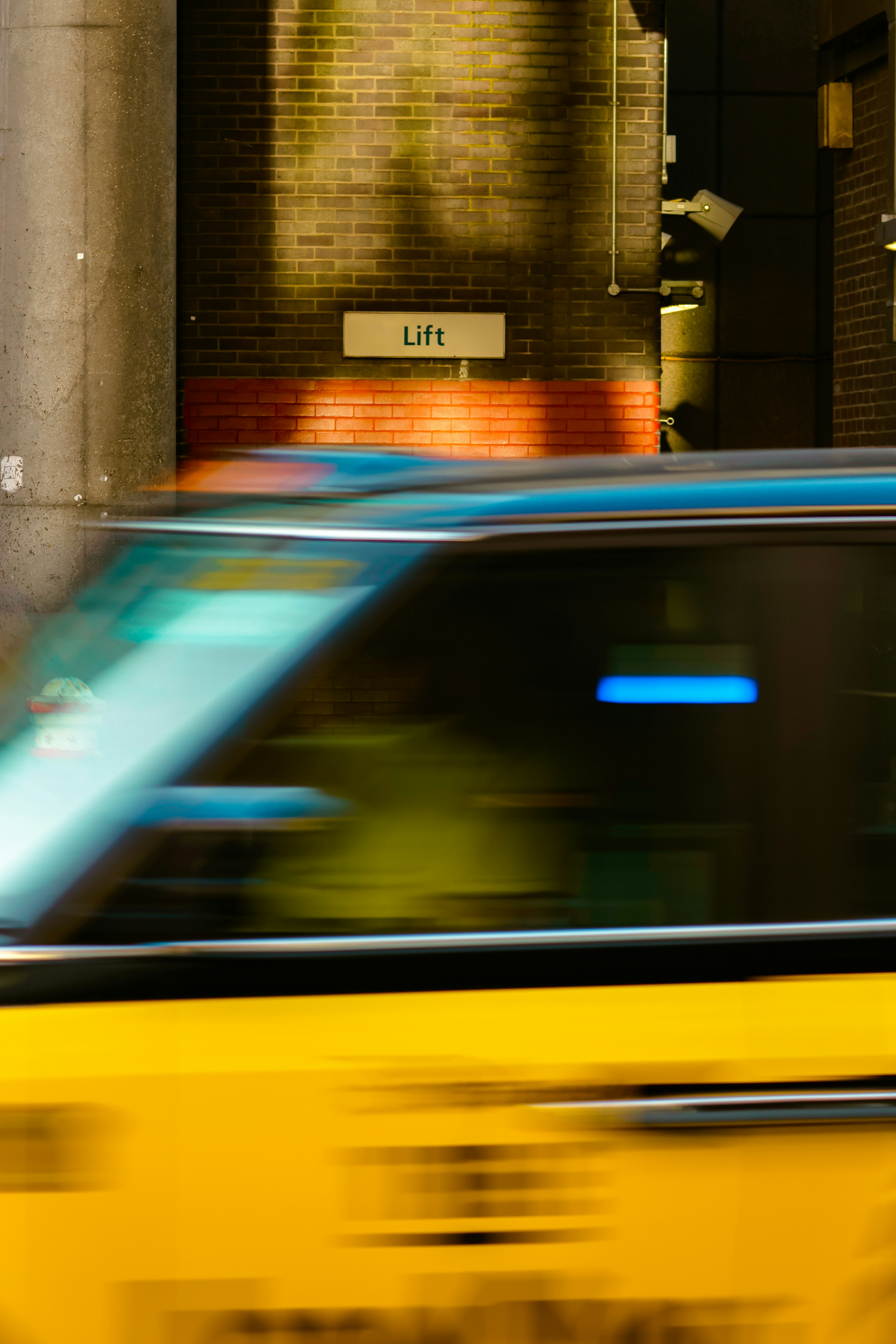 A yellow cab speeds past a building sign.