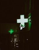 A pharmacy sign glows green at night.